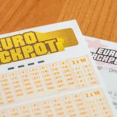 Kupony gry Eurojackpot z zaznaczonymi numerami na drewnianym tle.