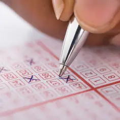 Ręka zaznacza liczby na kuponie lotto. Czy to kupon na loterię RMF o której godzinie?