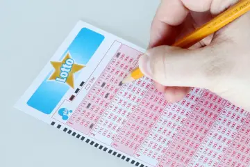 Ręka zaznacza liczby na kuponie Lotto, przygotowując się do losowania Eurojackpot.