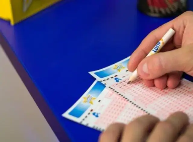 Ręka z ołówkiem z napisem LOTTO zaznacza liczby na kuponie. Czy to sztuczka, jak przewidzieć numery lotto?
