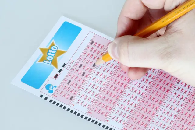 Ręka zaznacza liczby na kuponie Lotto, przygotowując się do losowania Eurojackpot.